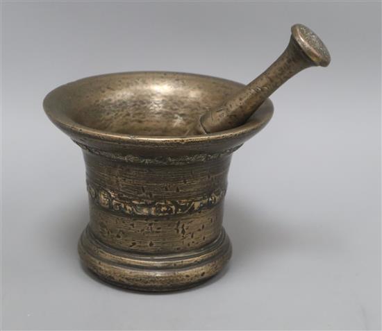 A 17th century bronze mortar inverted bell shape with scroll and shell design, a matching pestle, possibly The Whitechapel Foundry